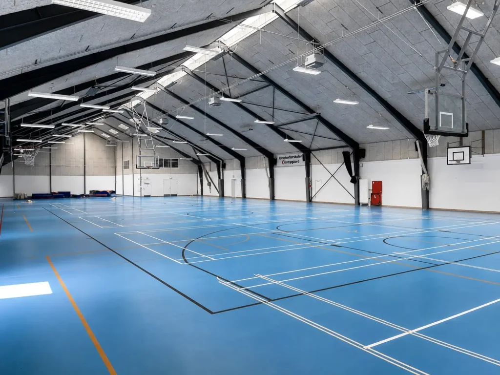 Renoveret sportshal med blå gulvoverflade og røde, orange, hvide og sorte banelinjer